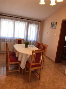 a dining room table and chairs with a white table and windows at Къща за гости Загорски in Kalofer