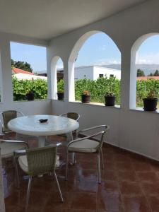 a white table and chairs in a room with windows at Rooms Ajllin in Ulcinj