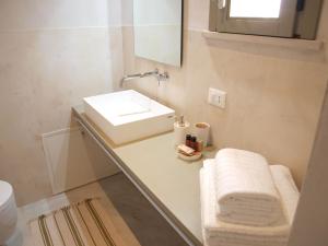 bagno bianco con lavandino e specchio di Casa vacanze "Officina del fabbro" - Menfi a Menfi