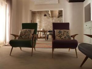 sala de estar con 2 sillas y mesa en Casa vacanze "Officina del fabbro" - Menfi, en Menfi