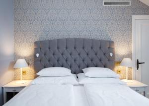 a bedroom with a large white bed with two lamps at Schloss Fellin Boutique Hotel and Spa in Viljandi