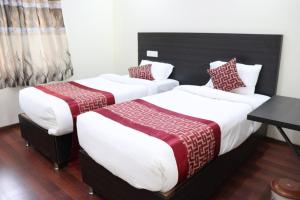 two beds in a hotel room with white and red sheets at Venster Residency in Chennai