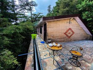 a deck with two tables and a small building at Jakhu Vibes in Shimla