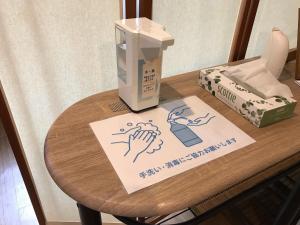 une table avec un panneau au-dessus d'une table avec une machine dans l'établissement 民宿さざんか, à Okinawa