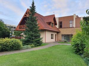 a house with a pine tree in the yard at Apartamentai Hunter house in Druskininkai
