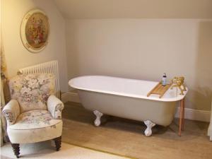 a bath tub sitting in a room with a chair at Sycamore cottage in Matlock