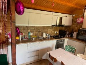 a kitchen with white cabinets and a sink and a table at Vila H2O in Mangalia