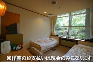 a room with two beds and a window in it at Hotel Kaminoyu Onsen in Kai