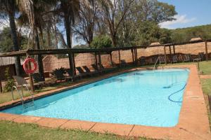 a swimming pool in a yard with chairs around it at Zebra Nature Reserve in Cullinan