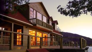 Casa con ventanas y terraza con mesas. en Terra Luna Lodge, en Puerto Guadal