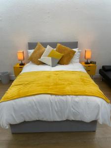 um quarto com uma cama grande com lençóis e almofadas amarelos em Balco City Living em Nottingham