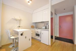 une cuisine avec des placards blancs et une porte rouge dans l'établissement Jõe Apartment, à Tallinn