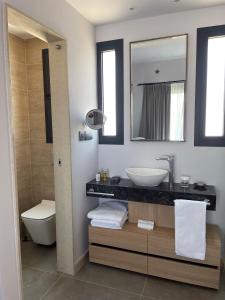 a bathroom with a sink and a toilet and a mirror at Windhill Edge Villa in Pissouri