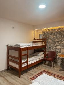 ein Schlafzimmer mit einem Etagenbett in einem Zimmer mit einer Steinmauer in der Unterkunft Riverside Guesthouse in Vusanje