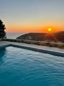 una piscina con puesta de sol en el fondo en Windhill Edge Villa, en Pissouri