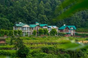 a row of houses on a hill with trees at Cottages @ Village in Bhīm Tāl