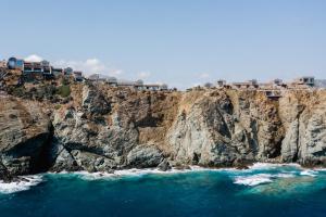 a cliff with houses on it next to the ocean at Acro Suites - A Wellbeing Resort in Agia Pelagia