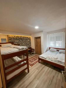 1 Schlafzimmer mit 2 Etagenbetten und Ziegelwand in der Unterkunft Riverside Guesthouse in Vusanje