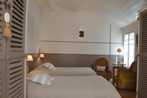 a hotel room with two beds and a window at Hotel Les Bois Flottais in Le Bois-Plage-en-Ré
