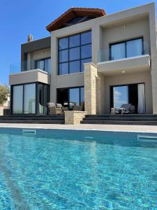 a house with a swimming pool in front of it at Windhill Edge Villa in Pissouri