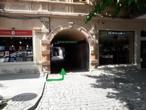 a tunnel entrance to a building with a green arrow at Hostel City Center in Kutaisi