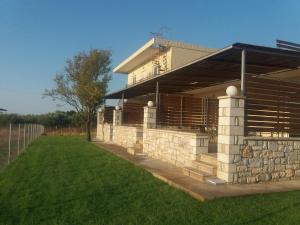 a house with a stone wall and a yard at Nereids Apartments-Agavi in Petalidhion