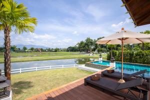 a patio with an umbrella and a swimming pool at Thantara Resort Chiang Mai in Chiang Mai