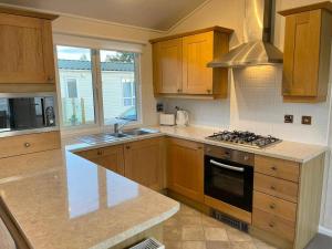 eine Küche mit Holzschränken und einem Herd mit Backofen in der Unterkunft Modern House in Carlisle close to Lake District in Carlisle