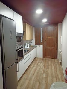 a kitchen with a stainless steel refrigerator and wooden cabinets at Casa Rural El Mirador de San Miguel in San Esteban de Gormaz