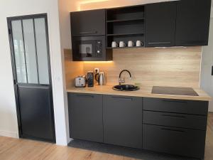 a kitchen with black cabinets and a black refrigerator at VIVEZ LE QUAI - St Francois - Notre Dame - PARKING in Le Havre