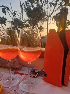 two glasses of wine on a table with a bottle at Casa Tina in Pomonte