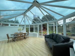 une véranda avec un canapé, une table et des chaises dans l'établissement 3 Bed Bungalow in Winchcombe, Cotswolds,Gloucester, à Winchcombe