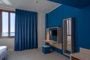 1 dormitorio con paredes azules, TV y cama en Isola di San Servolo - Centro Soggiorno, en Venecia