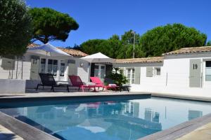 a swimming pool in front of a house at Hotel Les Bois Flottais in Le Bois-Plage-en-Ré
