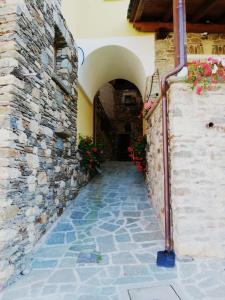 un callejón en un edificio con una pared de piedra y flores en Il Mulinel agriturismo en Teglio