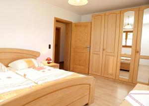 - une chambre avec un grand lit et des placards en bois dans l'établissement Haus Billinger, à Truchtlaching