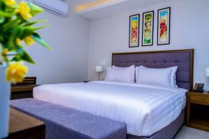 una camera da letto con un grande letto bianco e alcuni fiori di Canary Hotel Kampala a Kampala