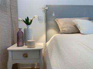 - un lit avec table de chevet et vase dans l'établissement NEU CasaBlanca - Haus am Meer, à Fuzeta