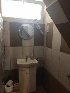 a bathroom with a sink and a clock on the wall at Balogh vendégház II in Szeged