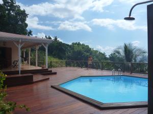 eine Frau steht auf einem Deck neben einem Swimmingpool in der Unterkunft Les jardins de Cousinière in Vieux-Habitants