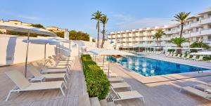 einen Pool mit Liegestühlen und Sonnenschirmen neben einem Hotel in der Unterkunft Globales Cala Bona in Cala Bona