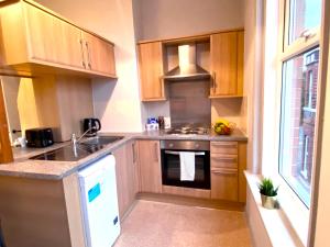 a kitchen with wooden cabinets and a stove top oven at Funky Stylish Apartment! - 5 Minute Walk to the Best Beach! - Great Location - Parking - Fast WiFi - Smart TV - Newly decorated - sleeps up to 4! Close to Bournemouth & Poole Town Centre & Sandbanks in Bournemouth