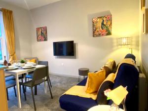 a living room with a blue couch and a table at Funky Stylish Apartment! - 5 Minute Walk to the Best Beach! - Great Location - Parking - Fast WiFi - Smart TV - Newly decorated - sleeps up to 4! Close to Bournemouth & Poole Town Centre & Sandbanks in Bournemouth