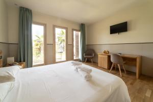 Schlafzimmer mit einem weißen Bett, einem Schreibtisch und einem TV in der Unterkunft Plana Resort & SPA in Castel Volturno