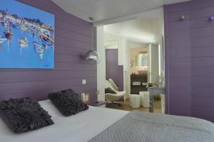 a bedroom with purple walls and a bed with pillows at Hotel Les Bois Flottais in Le Bois-Plage-en-Ré