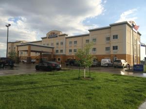 a large building with cars parked in a parking lot at Baymont by Wyndham Minot in Minot