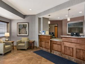 a lobby with a waiting area with chairs and a bar at Baymont by Wyndham Minot in Minot