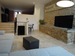 een woonkamer met een bank en een flatscreen-tv bij La Bourgade in Céreste