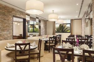 a dining room with tables and chairs and windows at Ramada Hotel & Suites by Wyndham Ajman in Ajman 