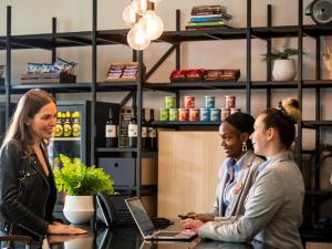 Tre donne sedute al bancone in una caffetteria di Aparthotel Adagio London Stratford a Londra